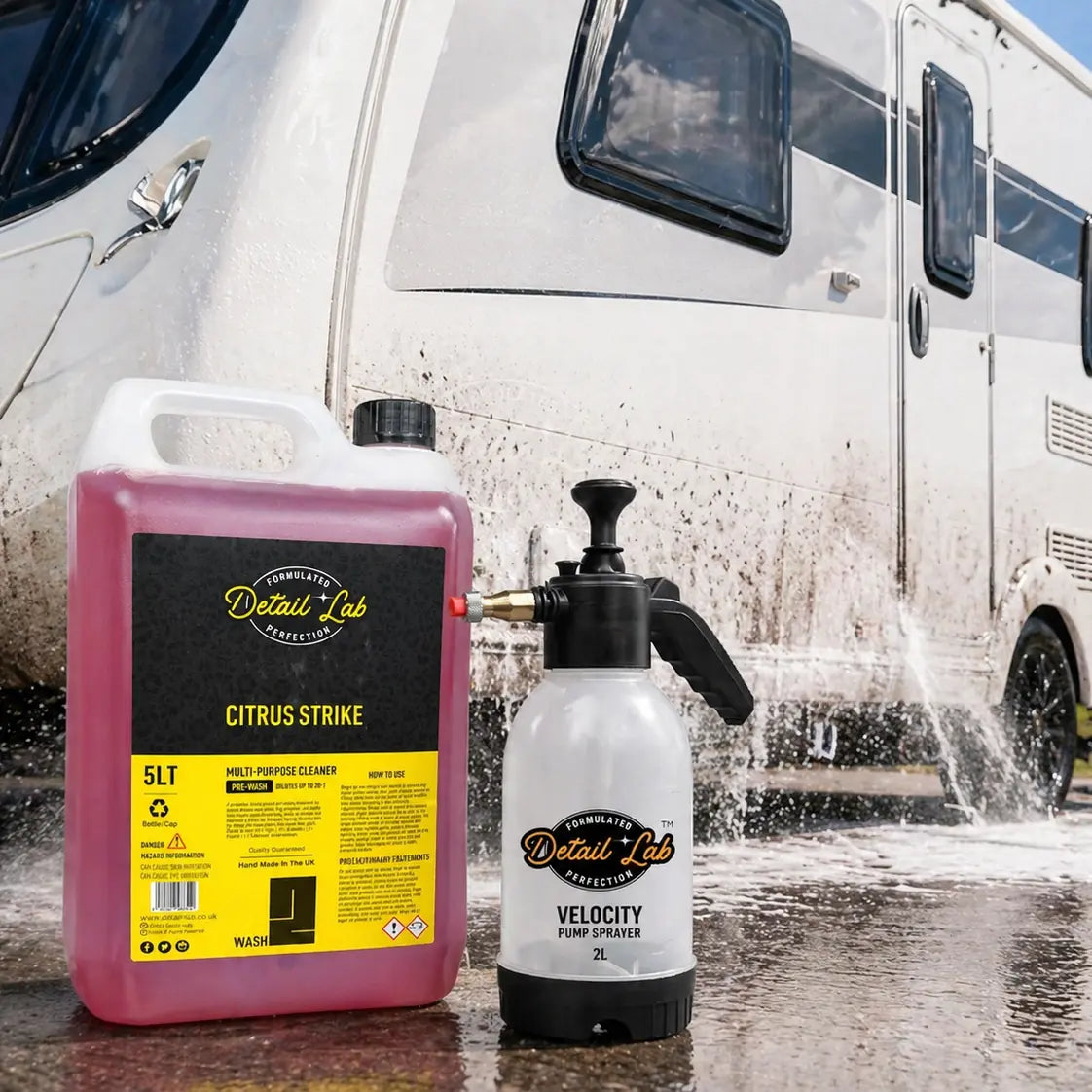 Two bottles of Detail Lab products in front of a white RV with water splashing.