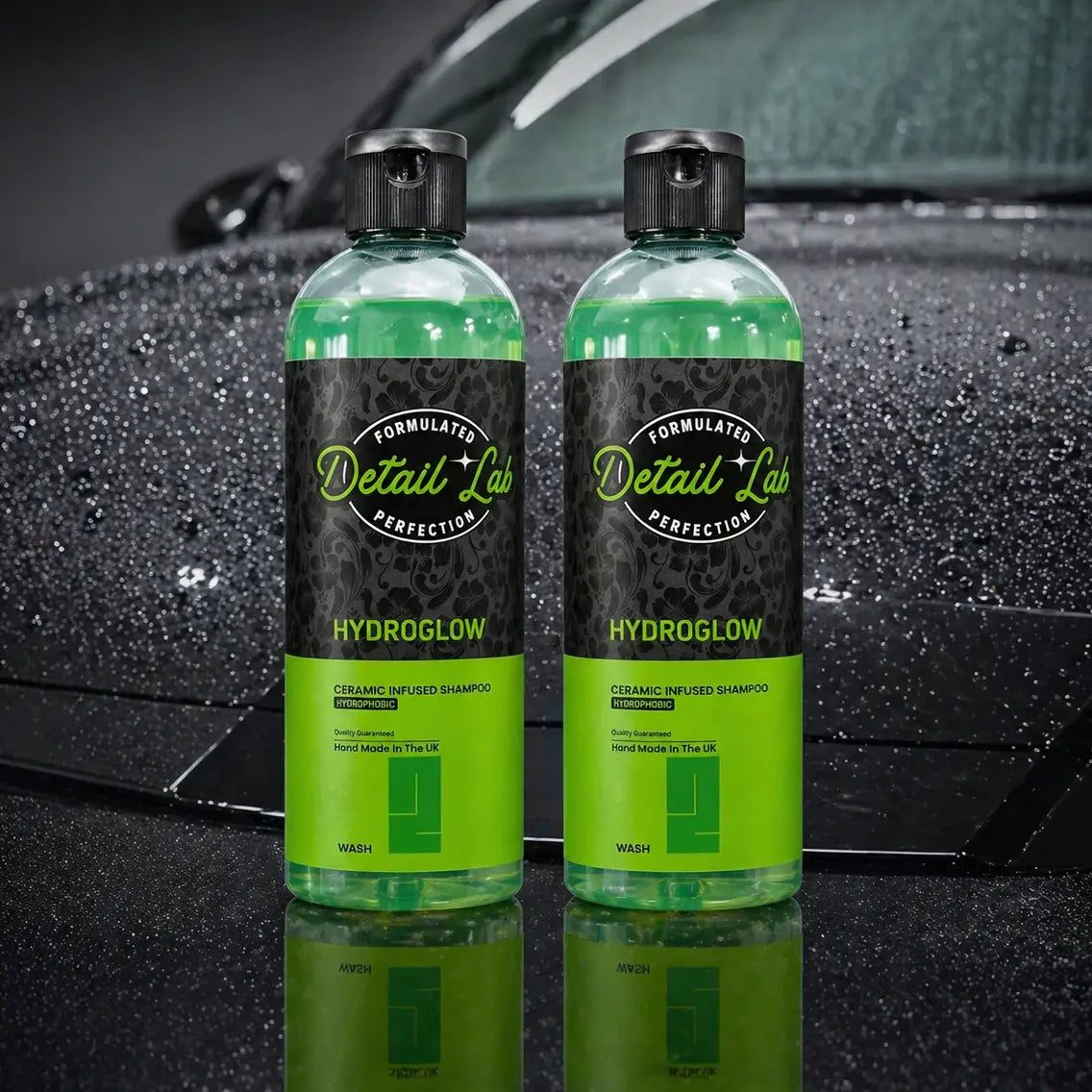 Two bottles of Detail Lab Hydroglow car wash product in front of a car.