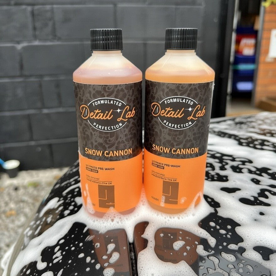 Two bottles of Detail Lab Snow Cannon on a car with soap suds.