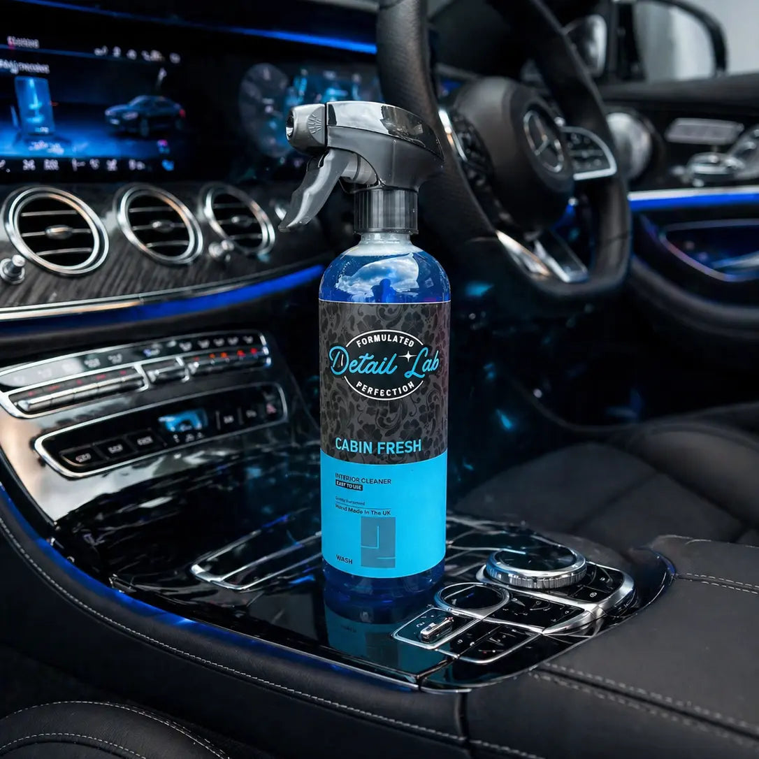 Car interior with a bottle of 'Detail 10' cabin freshener on the dashboard.