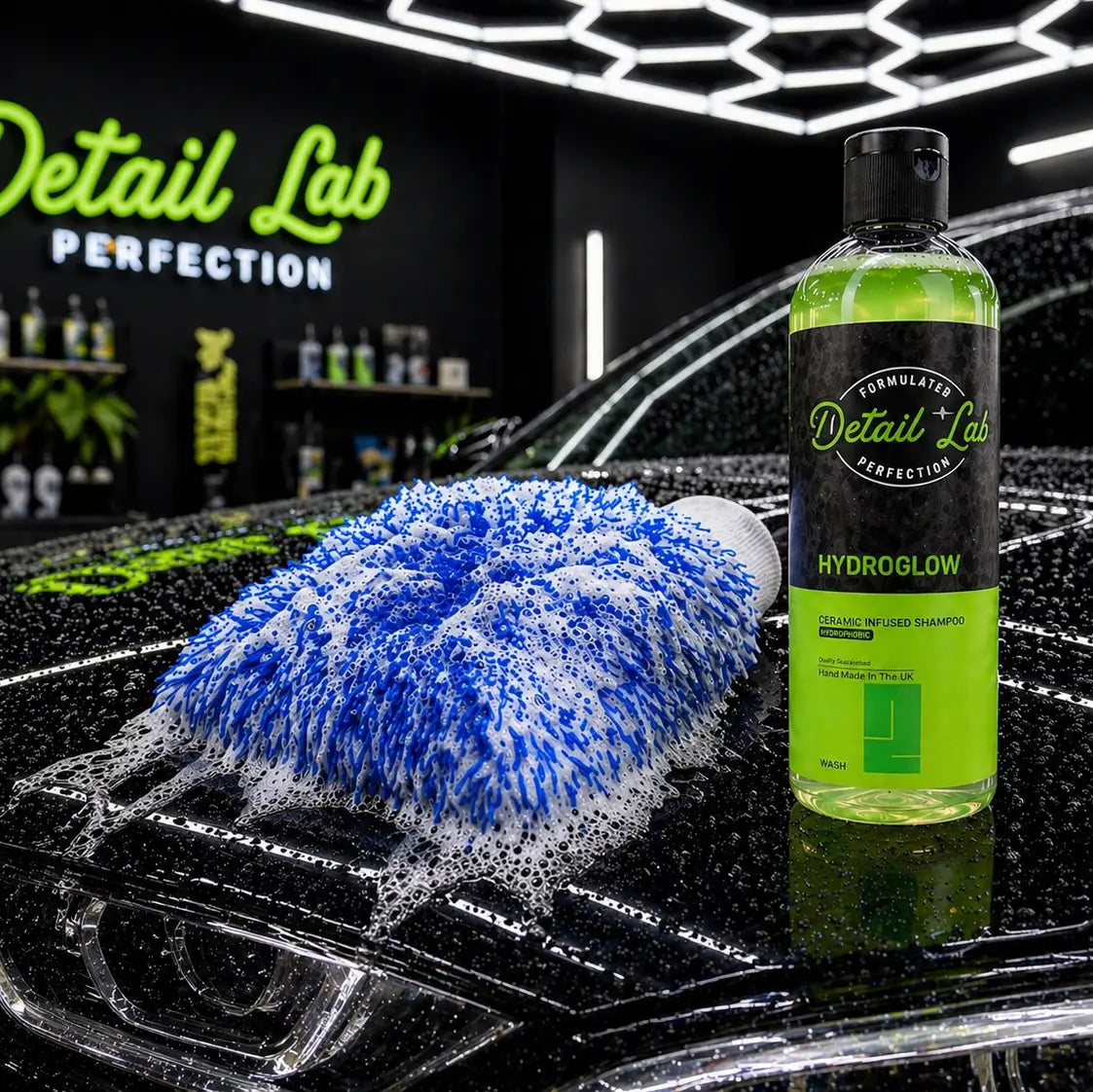 Car detailing products including a bottle of Detail Lab Hydroglow and a blue detailing towel on a car's hood.