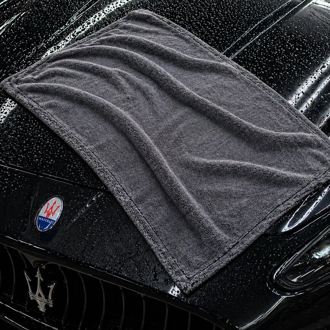 Gray towel draped over a black Maserati car